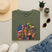 Olive green T-shirt with Mardi Gras queen and American flag graphic on front